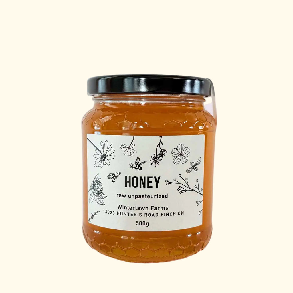 A 500g glass jar of Winterlawn Farms raw, unpasteurized honey.