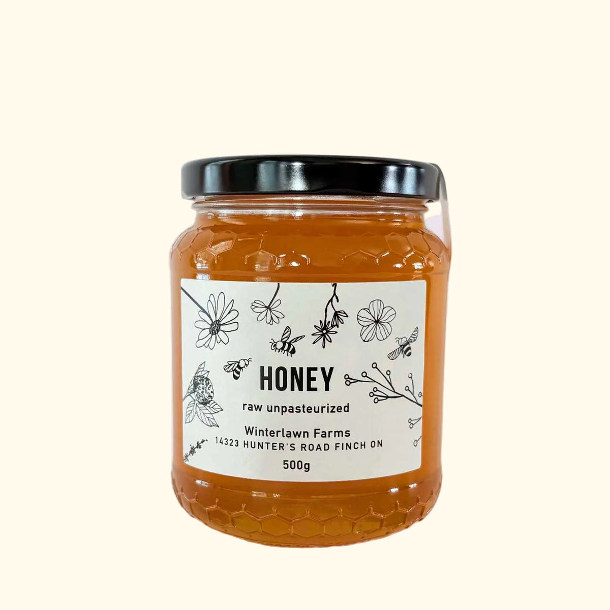 A 500g glass jar of Winterlawn Farms raw, unpasteurized honey.