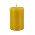 A single yellow hexagonal pillar candle with a short wick, standing upright on a light gray background.
