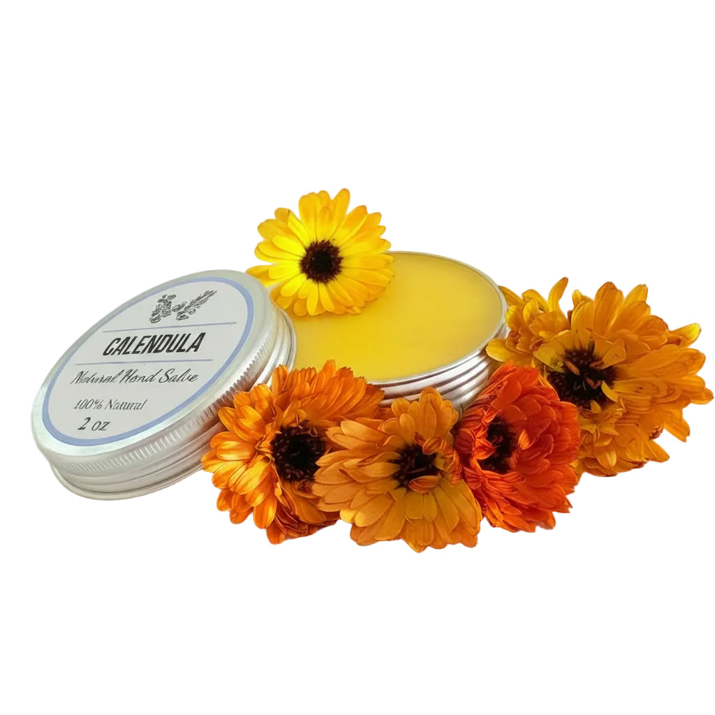 A round silver tin of Calendula Natural Facial Sticker shown open with yellow balm inside, surrounded by orange and yellow calendula flowers on a plain white background.