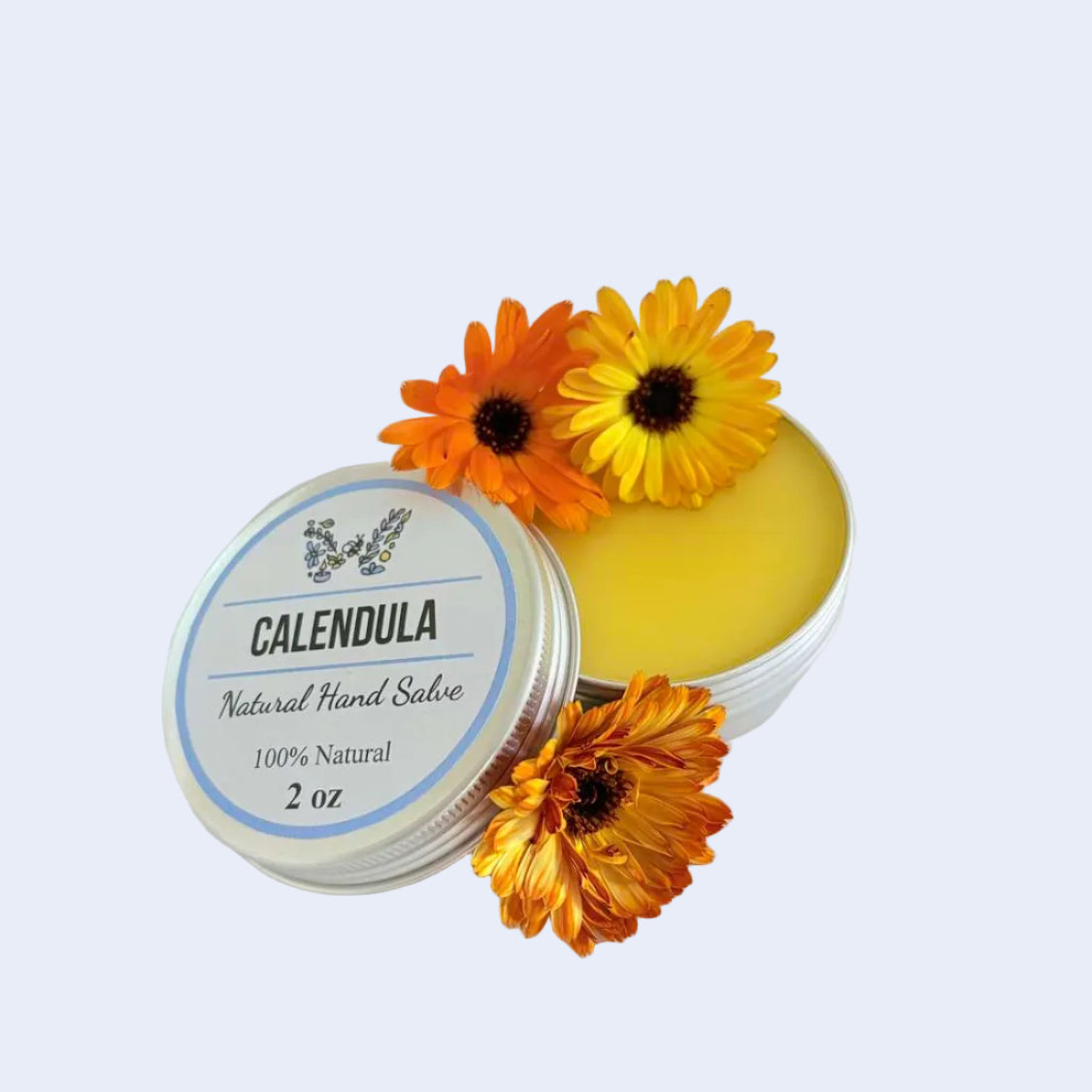 A round silver tin of Calendula natural hand salve, shown open with yellow balm visible and three orange calendula flowers placed on top and around it, on a plain white background.