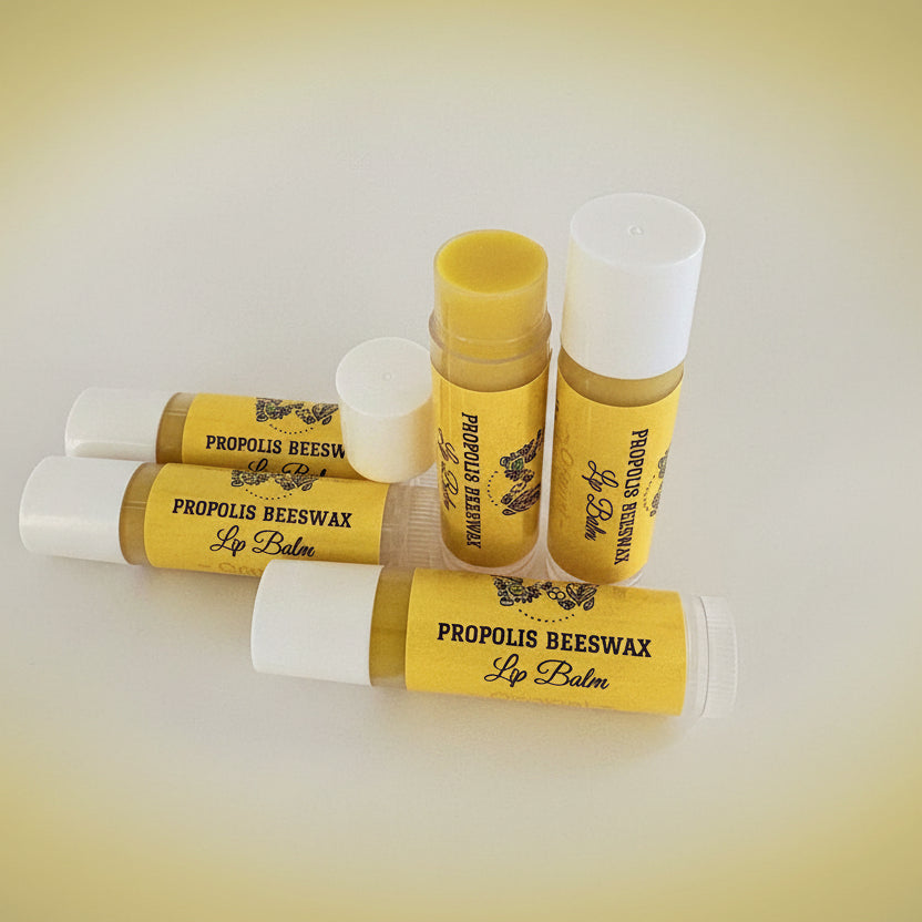 Five tubes of Propolis Beeswax Lip Balm arranged on a plain light background, with three closed white-capped tubes and two open tubes showing the yellow balm inside. The labels are bright yellow with black text and a bee graphic.