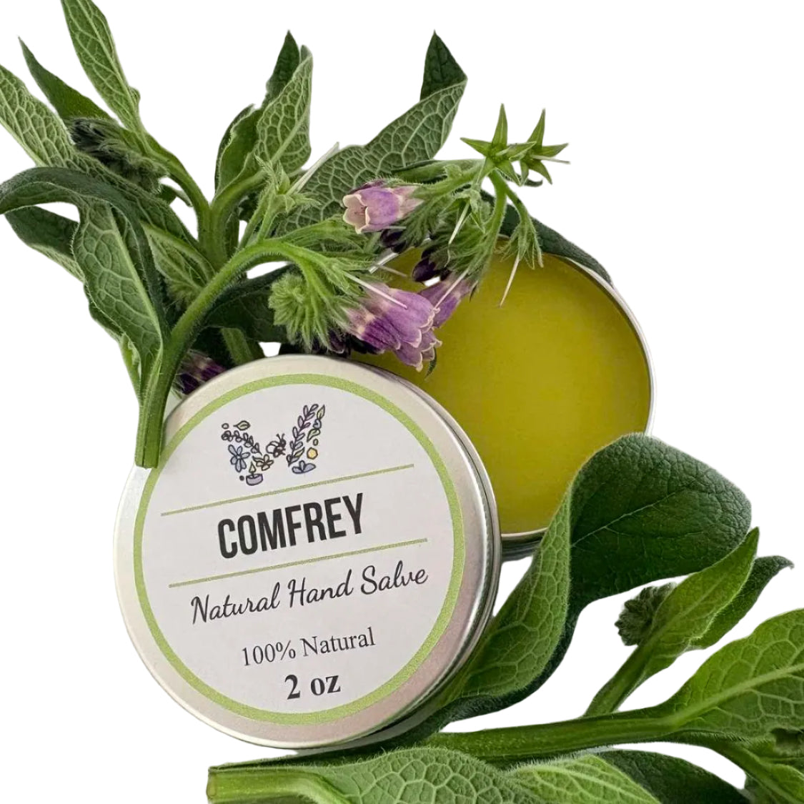 A round tin of Comfrey Natural Hand Salve with a white label, surrounded by fresh green leaves and purple borage flowers on a plain white background.